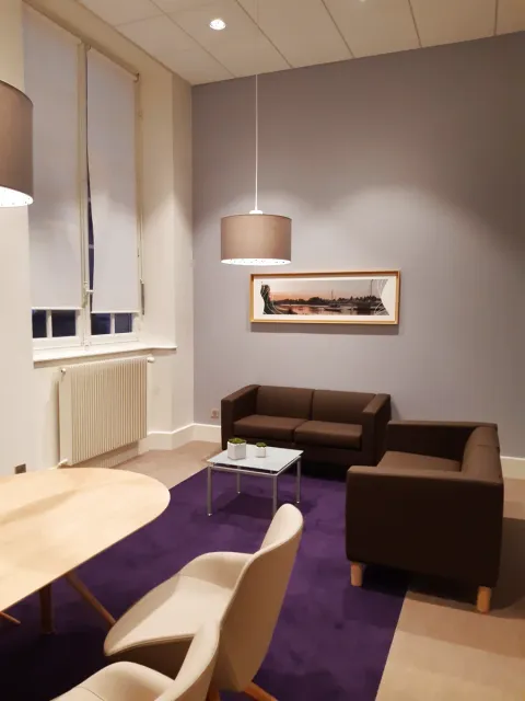 Salon de réception client d'une agence bancaire à Orléans avec banquettes, fauteuils et tapis violet